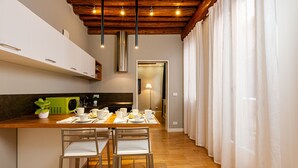 A modern kitchen with wooden beams, white cabinets, and a dining area with two chairs and a table set for four. - Two bedroom apartment with ensuite bathrooms in a perfect location. (Venezia)