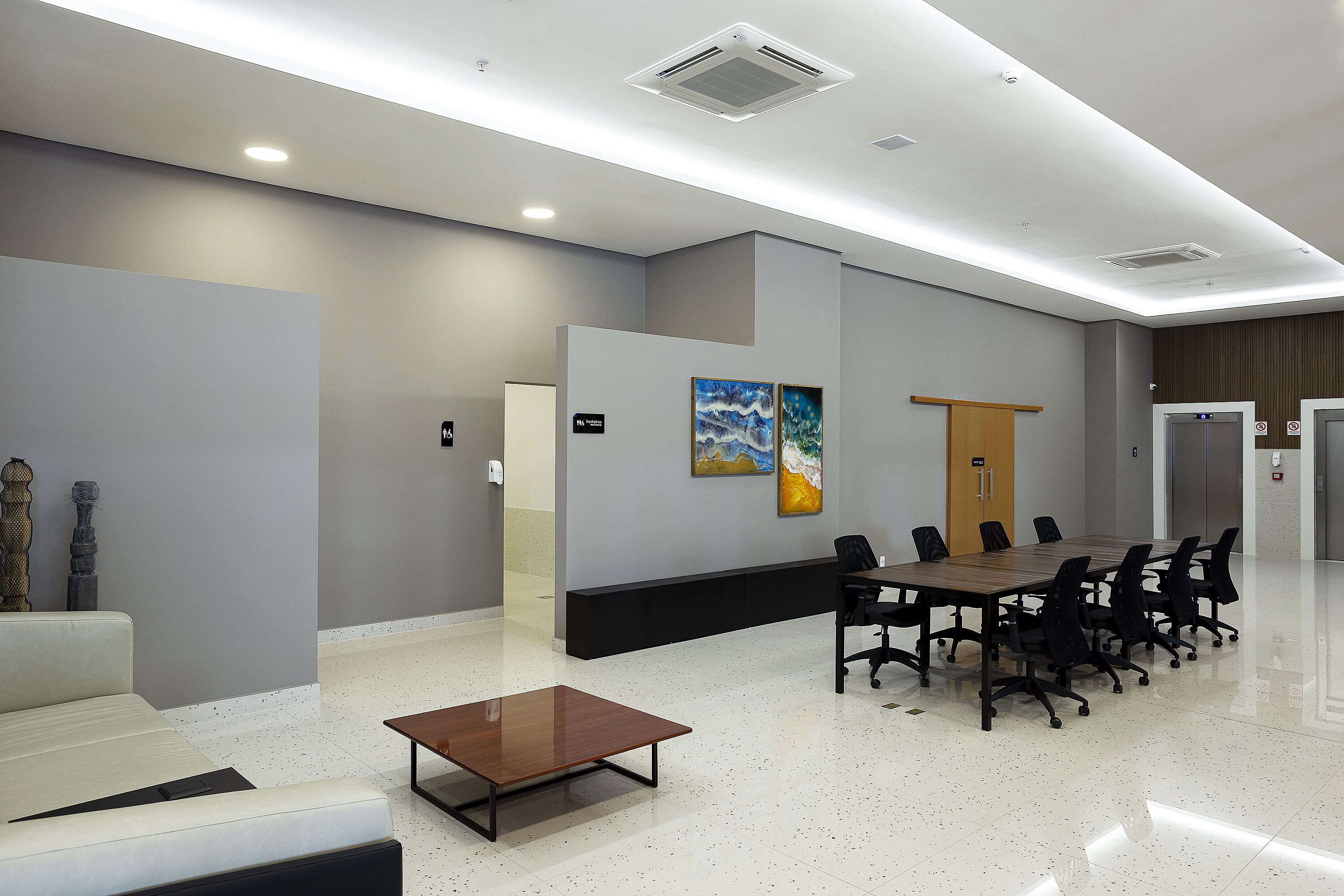 A modern conference room with a long table, chairs, a sofa, and artwork on the walls.