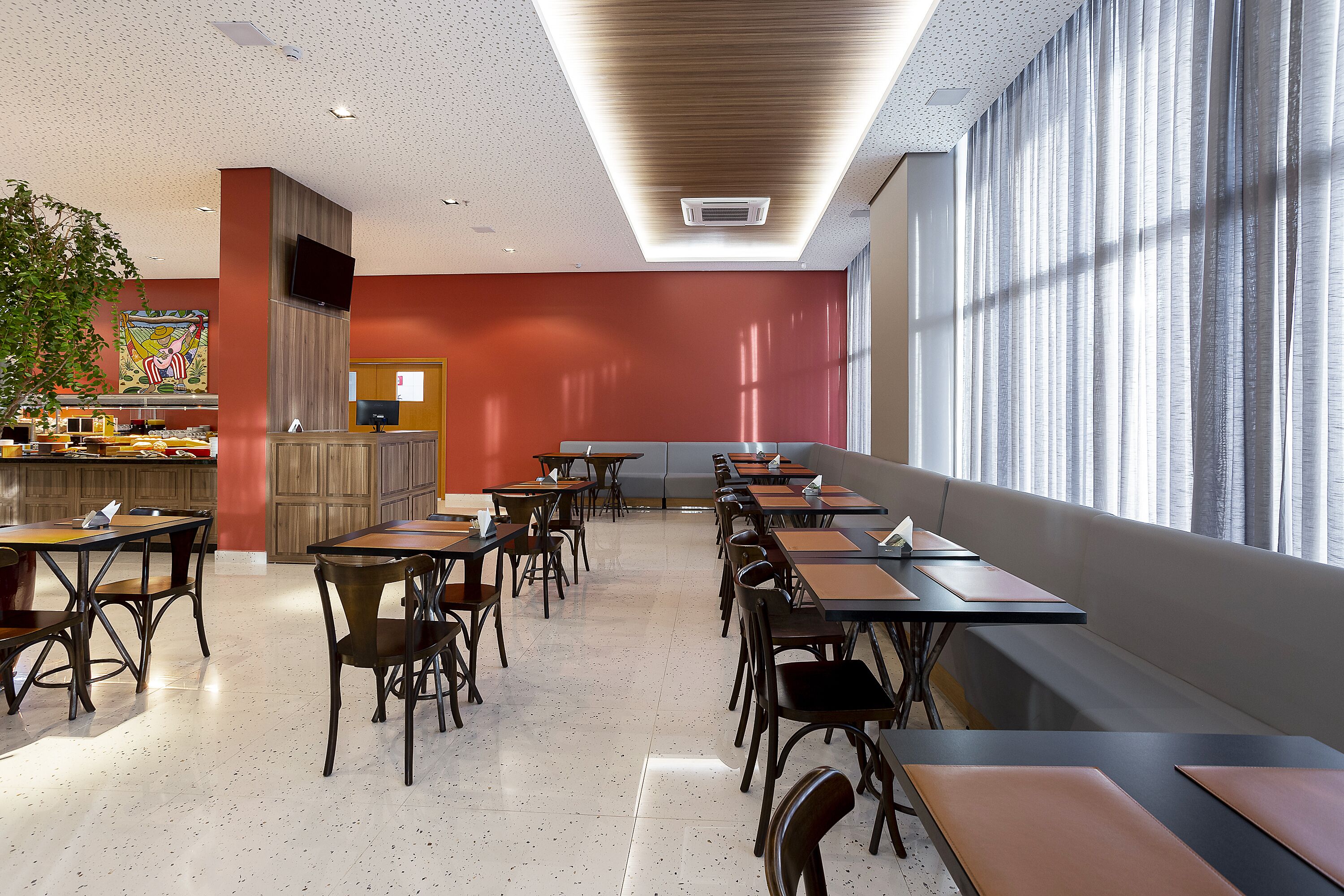 Un'area ristorazione moderna con tavoli, sedie, un bancone e un'ampia finestra.