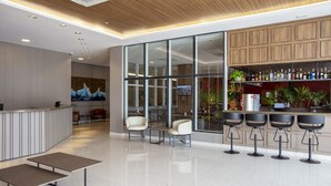 A modern bar area with a polished floor, bar stools, and a wooden cabinet with bottles. - Nacional Inn Rondonopolis (Rondonópolis)