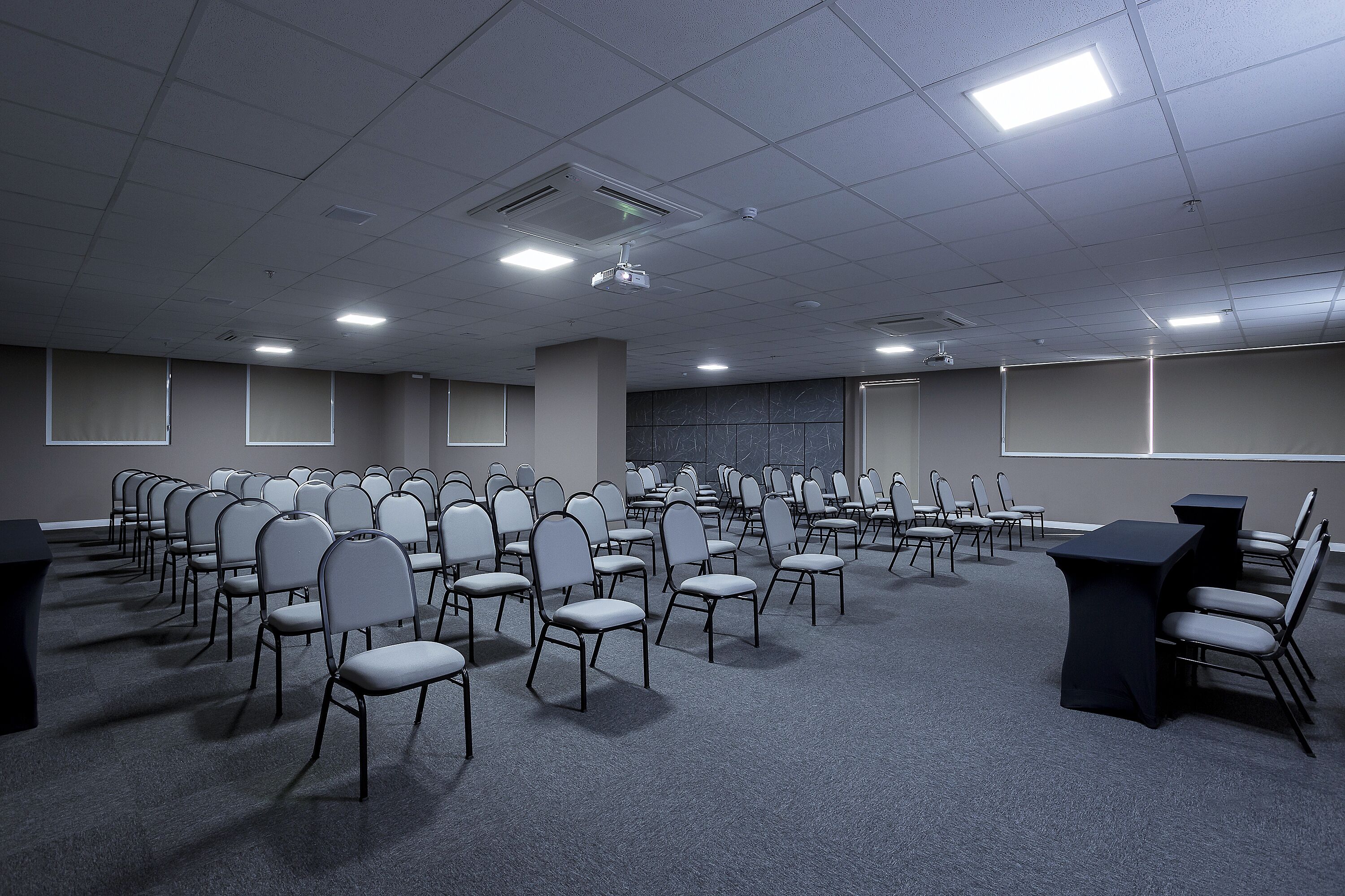A conference room with rows of chairs, a projector, and a screen.