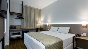 A hotel room with a bed, bedside tables, a desk, a chair, a TV, a coat rack, and a window with curtains. - Nacional Inn Rondonopolis (Rondonópolis)