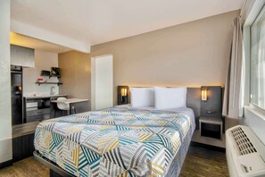 Une chambre d’hôtel de taille réduite, comprenant un lit, une table de chevet et un petit bureau avec une chaise.
