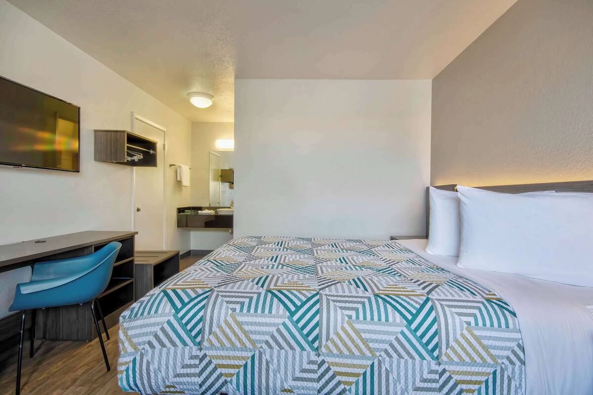 Een hotelkamer met een bed, een bureau, een stoel en een spiegel.