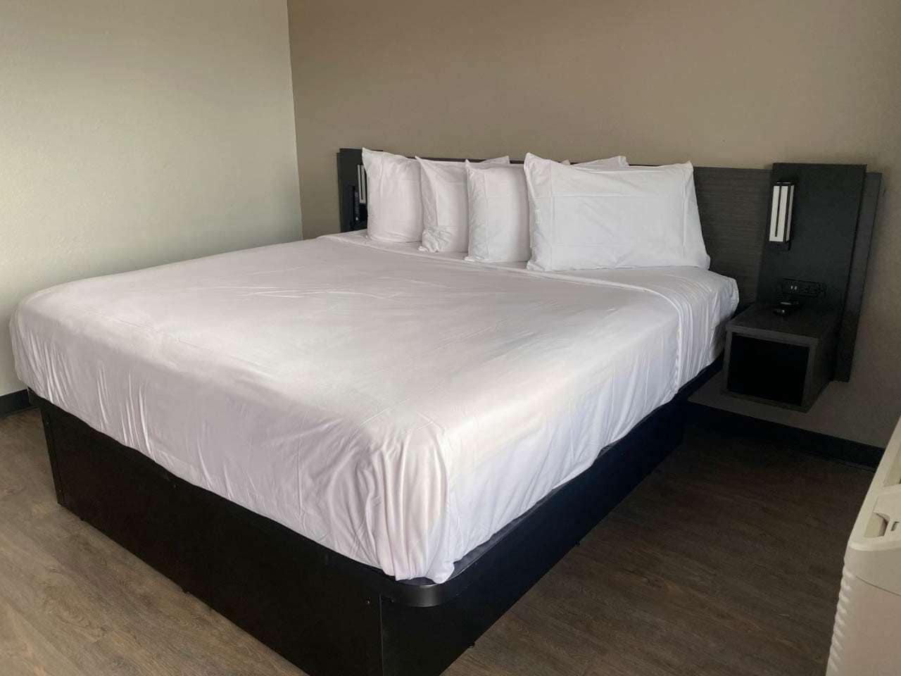 A neatly made bed with white linens in a hotel room.