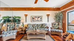 A living room with a ceiling fan, a sofa, two armchairs, a coffee table, and a large window. - Private Oceanfront Penthouse Lae Nani 231, New split A/C, Parking, AMAZING VIEW! (Kapaʻa)