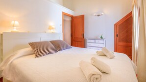 A neatly made bed with pillows, a bedside lamp, and a rolled towel on the bed. - Casa Torres (Pollensa / Pollença)
