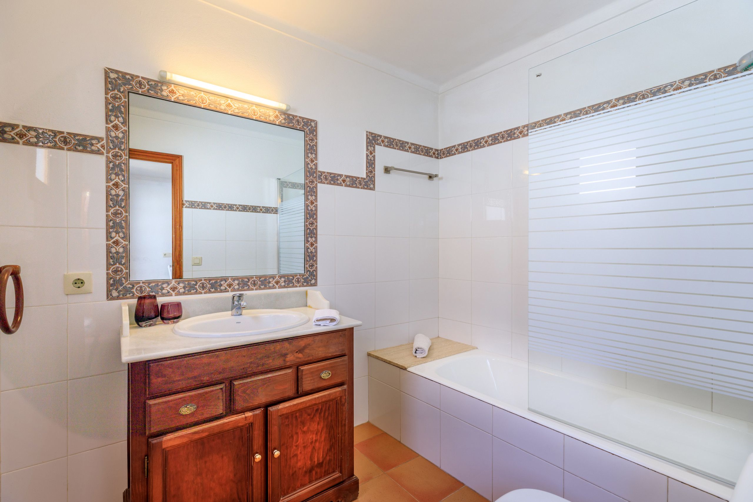 A bathroom with a wooden vanity, a large mirror, a sink, and a bathtub.