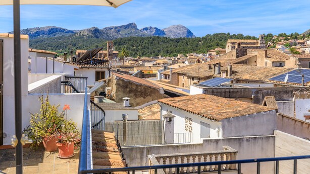 A terrace with potted plants, a view of a town with traditional architecture, and mountains in the background. - Casa Torres (Pollensa / Pollença)