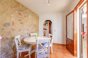 A dining area with a round table, white chairs, and a stone-patterned wall. - Casa Torres (Pollensa / Pollença)