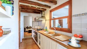 A kitchen with wooden beams, a large window, and a sink. - Casa Torres (Pollensa / Pollença)