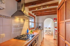 A kitchen with a gas stove, a range hood, and a window. - Casa Torres (Pollensa / Pollença)