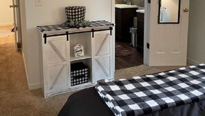 Een slaapkamer met een bed, een kaptafel, een spiegel en een deur naar een badkamer.