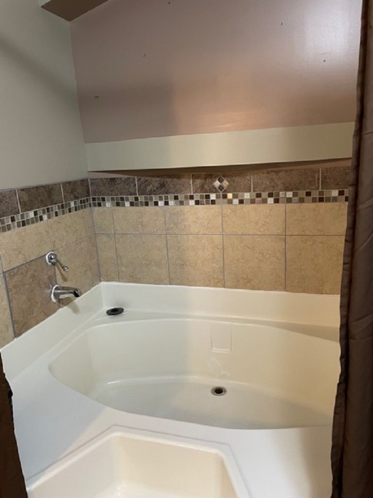 Ein Badezimmer mit einer großen Badewanne, gefliesten Wänden und einer Duschkabine.