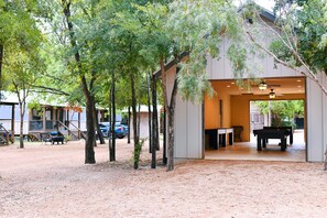 Un edificio con un espacio exterior techado, mesa de billar y ventilador de techo.