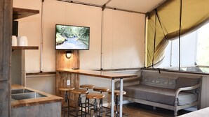 A compact, modern room with a wooden bar, bar stools, a cushioned bench, and a television mounted on the wall. - Brand new waterfront Cabin with many amenities: Pool, hot tub & kayaking. - SG2  (Seguin)