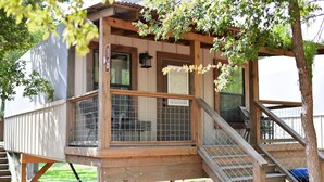A wooden structure with a covered porch, a staircase, and a fenced area.