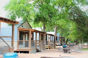 A row of cabins with outdoor seating and a covered area. - Wow! Brand new Creekfront Cabin! Hot tub, hiking, kayaking & more! - SG6  (Seguin)