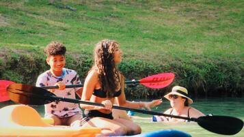 Three people in a kayak on a river.