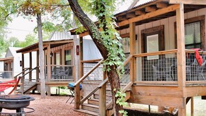 Un edificio rustico in legno con una zona esterna coperta, un braciere e un recinto.