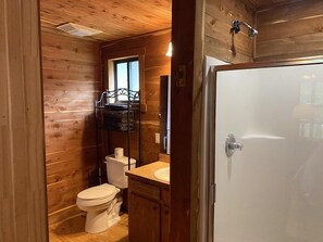 A wooden cabin bathroom with a toilet, sink, and shower. - Charming Cabin on the San Marcos River, comfortable, clean, fun, lots to do! L4 (Kingsbury)