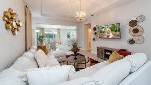 A modern living room with a sofa set, a coffee table, a TV, and decorative wall art. - Lovely Pool Home With Spa Close to Area Attractions (Davenport)