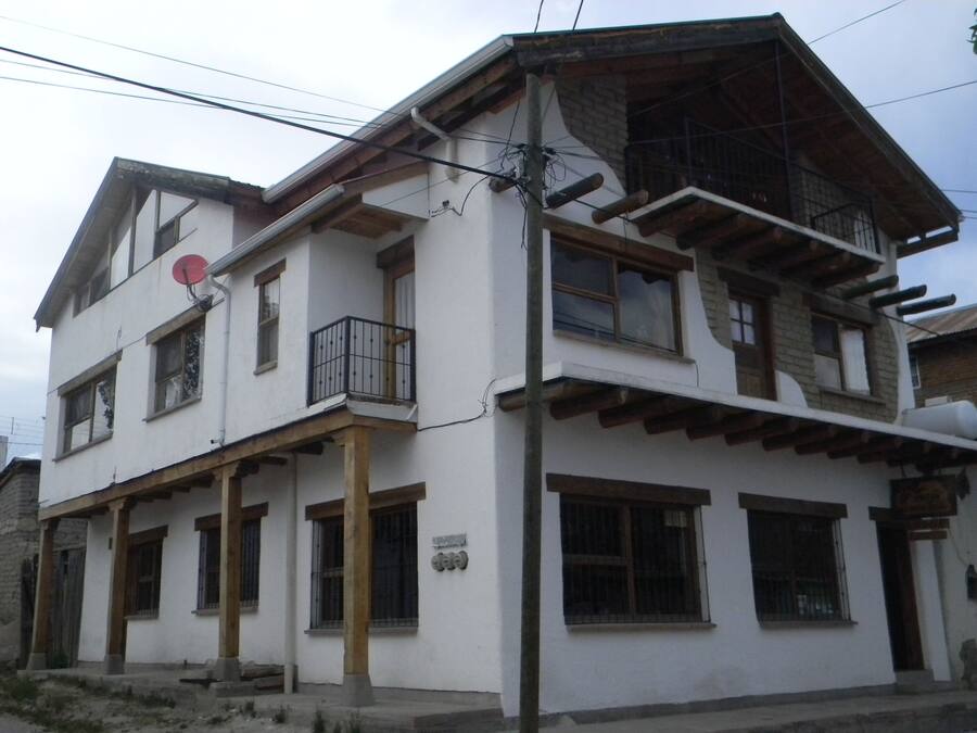 Un edificio de dos pisos con un balcón en la planta baja, una antena parabólica y una chimenea de ladrillo.