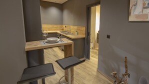 A modern kitchen with a wooden countertop, a sink, and a dining area with two stools. - Ubrique Rural Loft (Ubrique)