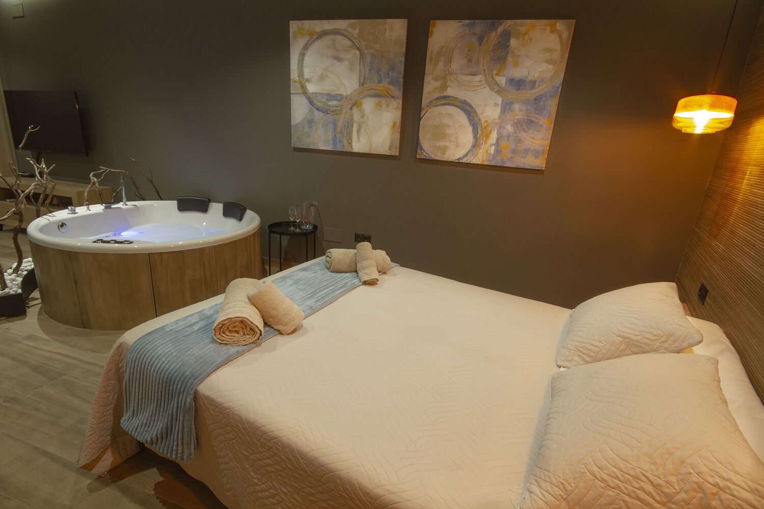 Une chambre d’hôtel avec un grand lit, une baignoire en bois et des œuvres d’art abstraites accrochées aux murs.