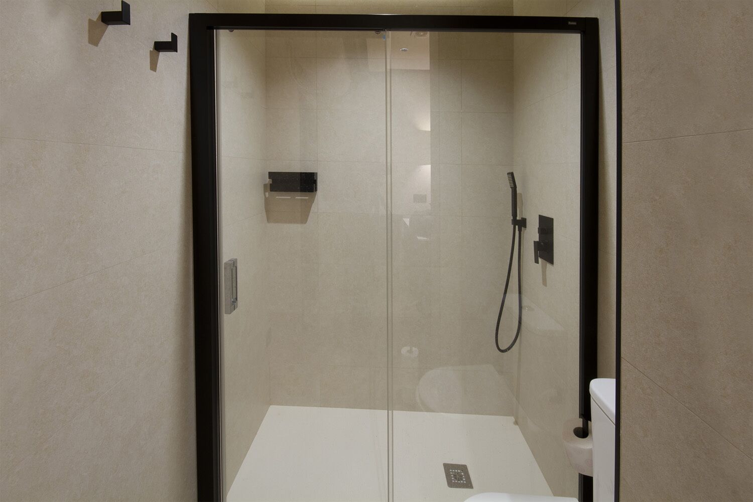 A glass-enclosed shower stall with a toilet and a towel rack.