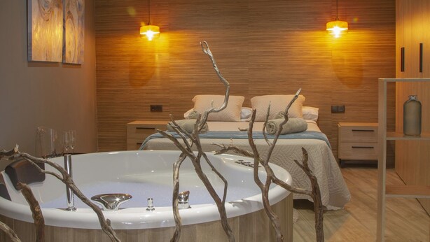 A modern bathroom with a freestanding bathtub, wooden wall paneling, and two bedside lamps. - Ubrique Rural Loft (Ubrique)
