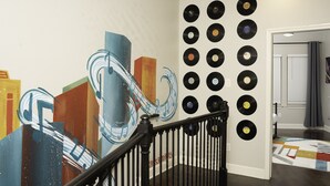 A staircase with a black railing, a wall with a colorful abstract mural, and a wall decorated with vinyl records.