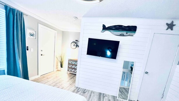 Ein Schlafzimmer mit einem Bett, einem an der Wand befestigten Fernseher und einer Wanddekoration mit Fischen.