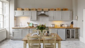 A modern kitchen with white cabinets, a wooden dining table, and a built-in oven.