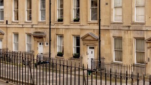 A row of traditional terraced houses with uniform window designs and a black metal fence in front.