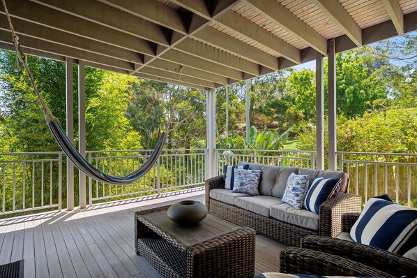 A covered outdoor seating area with a hammock, wicker furniture, and a view of lush greenery. - "Sea La Vie" - Perfect Holiday Getaway (Copacabana)