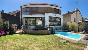 Una casa moderna de dos pisos con techo curvo, piscina y zona de terraza.