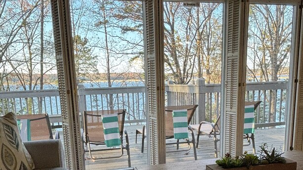 A cozy living room with a sofa, armchair, and coffee table, featuring a view of a deck and outdoor furniture.