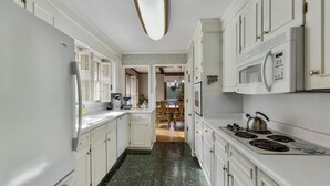 A kitchen with white cabinets, a stove, a microwave, and a refrigerator.