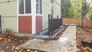A house with a front porch, a wooden fence, and a leaf-covered ground. - Modern Private Cottage Basement Unit  (Kirkland)