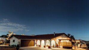 Een tweelaags huis met garage, gebogen ramen en een overdekte patio.
