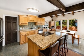 A modern kitchen with wooden cabinets, granite countertops, and a central island.