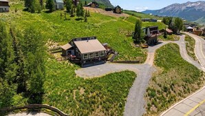 A mountain lodge with a central building surrounded by a winding road, set against a backdrop of mountains and greenery. - Pet Friendly, Great Views, Great For Large Groups (Crested Butte)