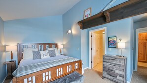 A bedroom with a wooden bed, a bench, a dresser, and a door leading to another room. - Pet Friendly, Great Views, Great For Large Groups (Crested Butte)