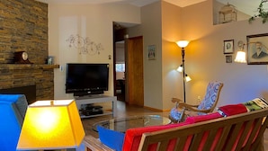 Una sala de estar con televisión, sofá, sillón y lámpara.