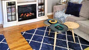Una sala de estar con televisión de pantalla plana, chimenea, sofá, mesa de centro y un adorno de pared.