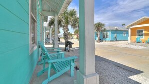 A turquoise building with a covered porch and outdoor seating. - Blue Wave~Community Pool~Family Friendly~Sleeps 10 (Port Aransas)