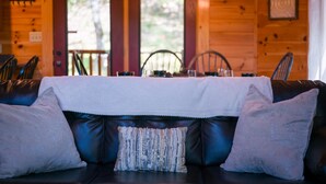 A wooden cabin interior with a leather sofa, a white tablecloth, and a chandelier. - Beautiful Autumn Season in The Smokies! Hot Tub! (Sevierville)