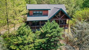 A log cabin with a balcony, surrounded by dense forest. - Beautiful Autumn Season in The Smokies! Hot Tub! (Sevierville)