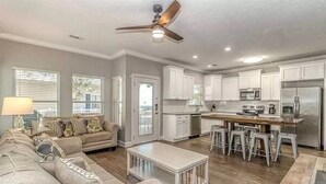A spacious living room with a sofa, coffee table, and a kitchen area with white cabinets, a refrigerator, and a microwave. - Welcome to Serinity on the Beach (Myrtle Beach)